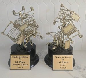 1st place trophies for both female and male winners. The trophy consists of a fun pile of shopping carts stacked up, referencing Crisis Assistance Ministry's Free Store, who is this year's beneficiary.